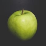 a green apple sitting on top of a black table